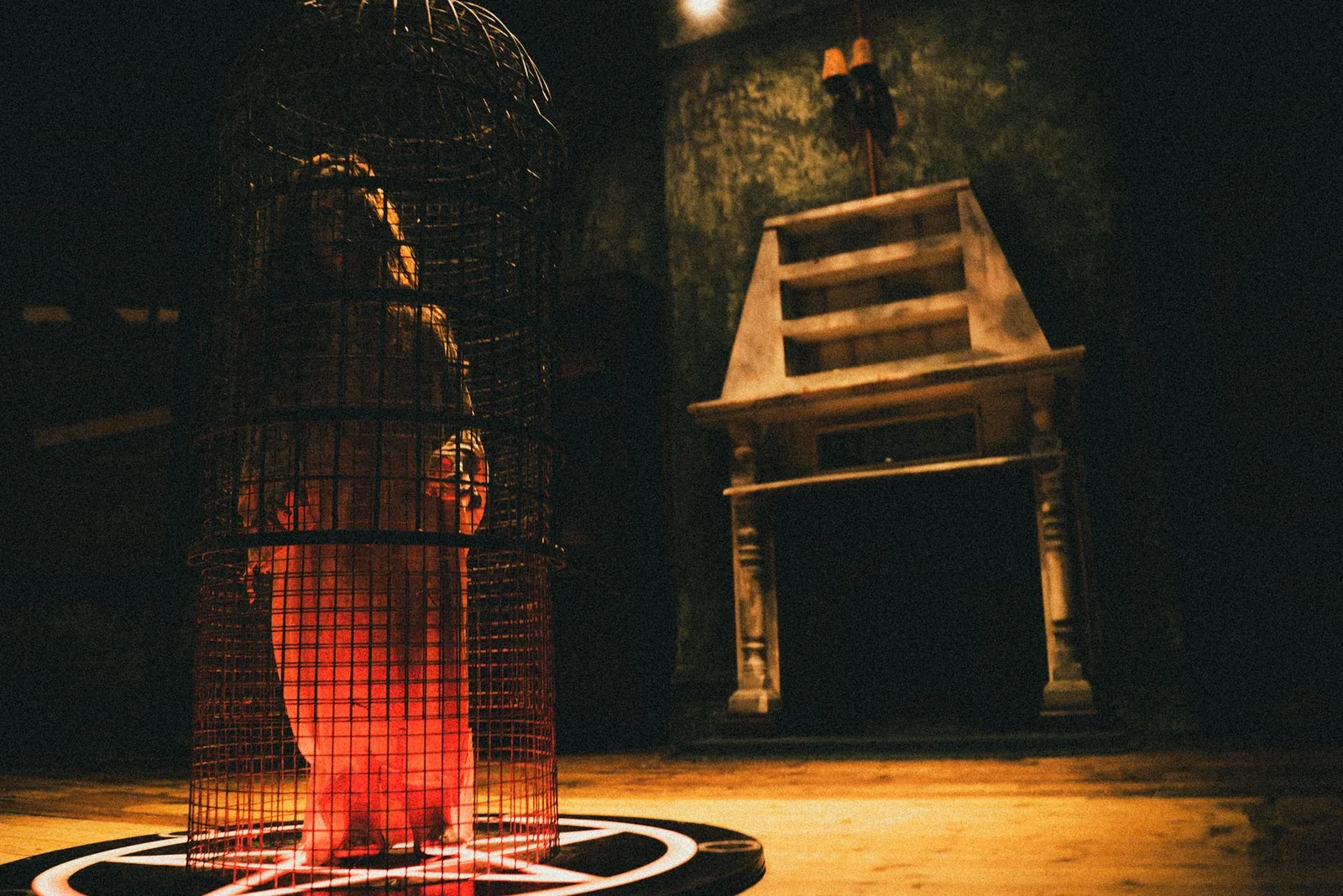 A glowing red birdcage on a pentagram in the parlour of The Haunting