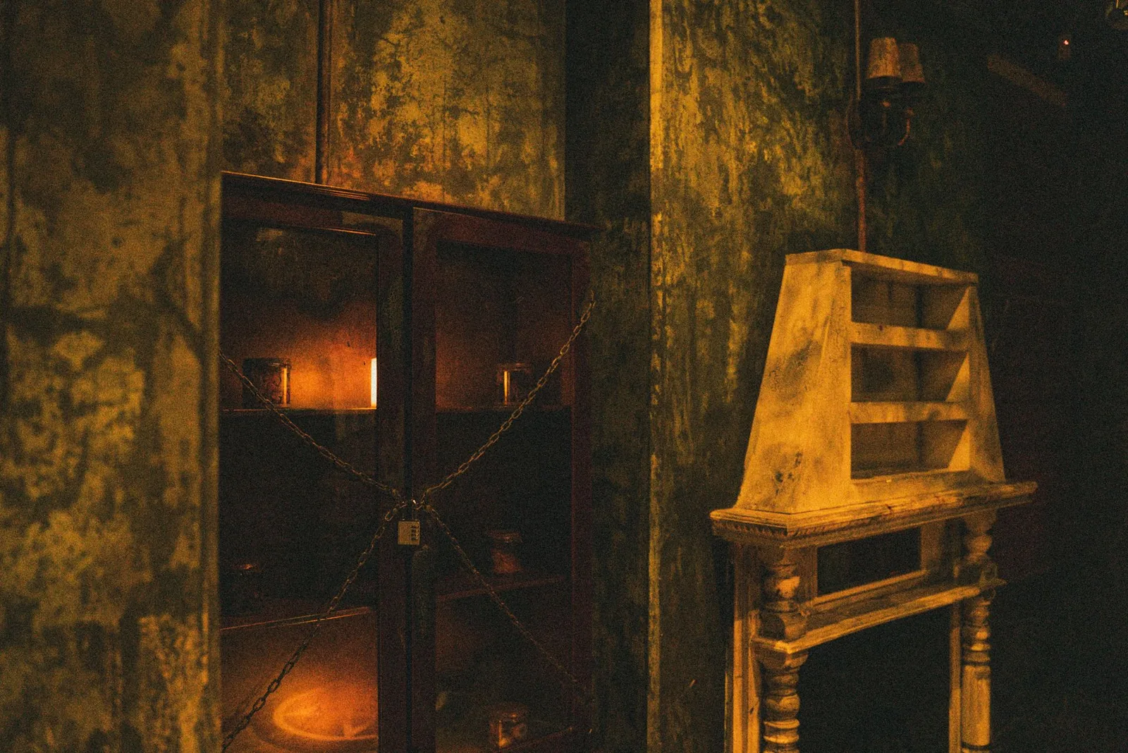 A cabinet chained and padlocked shut beside a candlelit fireplace in The Haunting