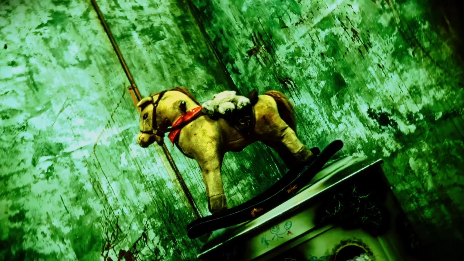 A battered rocking horse in green light in The Haunting